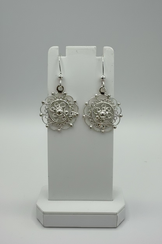Pair of sterling silver filigree circle earrings on a white stand with a grey backgroun
