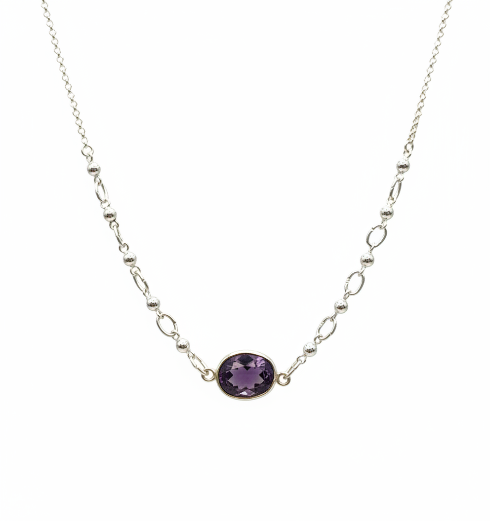 A silver chain necklace featuring a central bezel-set oval purple gemstone, shown against a plain white background.