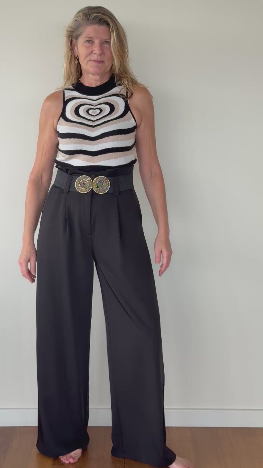 Video of woman with geometric knit tank top with heart design in neutral colours with black wide leg tailored pants with black belt.  Cheeky Goddess - Vida size 14 Australia