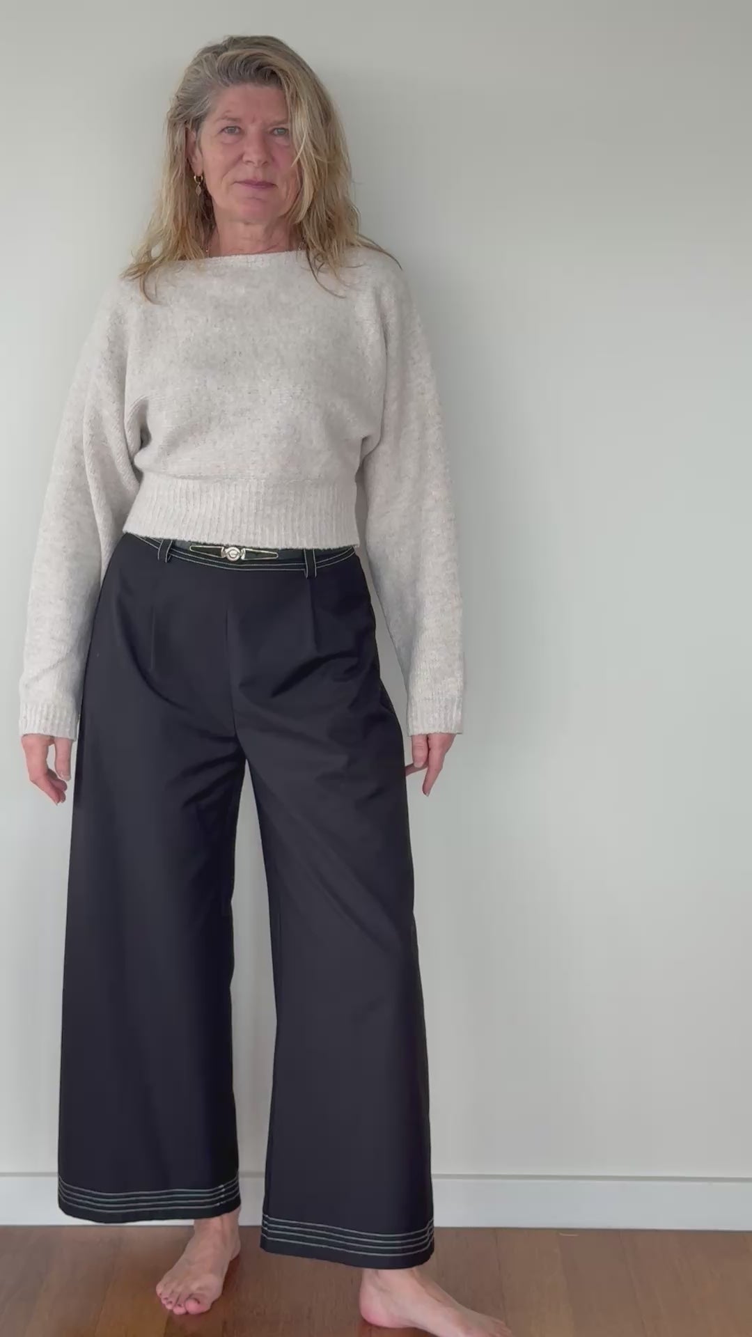 Video of woman in oatmeal coloured long sleeved waist length knit top.  With black wide leg pants with belt.  Cheeky Goddess - Vida size 14 - Australia